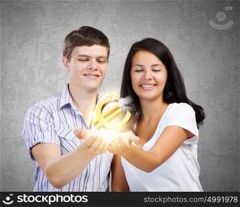Family budget. Young happy couple holding euro sign in palms
