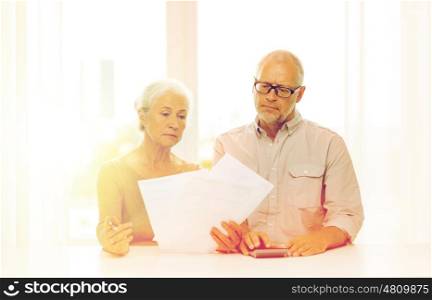 family, business, savings, age and people concept - senior couple with papers and calculator at home