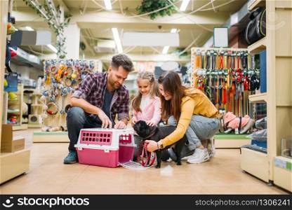 Family buying supplies for little puppy in petshop. Father, mother and dauther chooses accessories for dog in pet shop