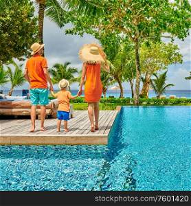 Family by poolside, young couple with three year old toddler boy. Resort swimming pool at Mahe, Seychelles.