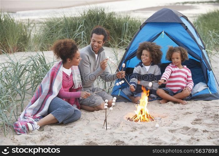 Family Camping On Beach And Toasting Marshmallows