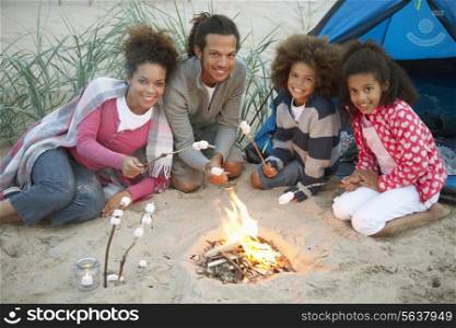 Family Camping On Beach And Toasting Marshmallows