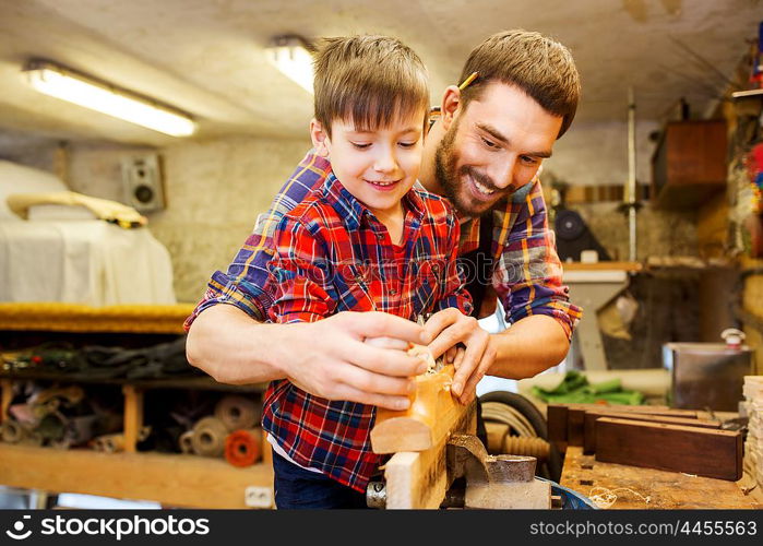 family, carpentry, woodwork and people concept - father and little son with plane working with wood plank at workshop