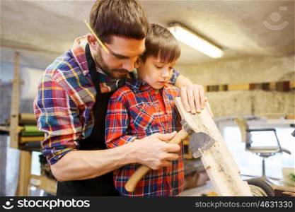 family, carpentry, woodwork and people concept - father and little son with ax and wood plank at workshop