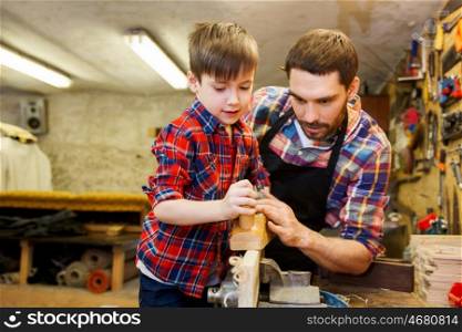 family, carpentry, woodwork and people concept - father and little son with plane working with wood plank at workshop