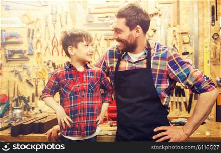 family, carpentry, woodwork and people concept - happy father and little son working with work tools and wood planks at workshop. happy father and little son workshop. happy father and little son workshop