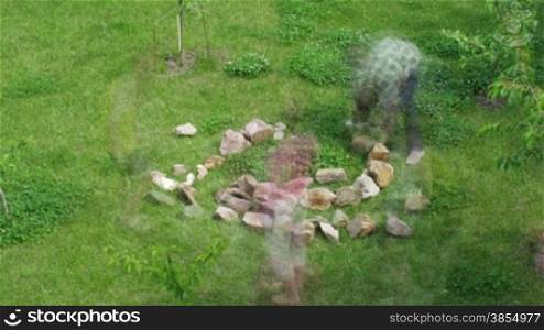 family carries stones for construction of flower bed.