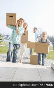Family carrying cardboard boxes while entering new house