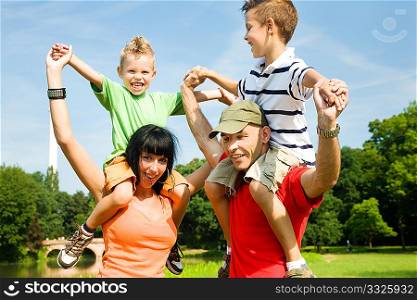 Family carrying their two kids piggyback under a perfect blue sky