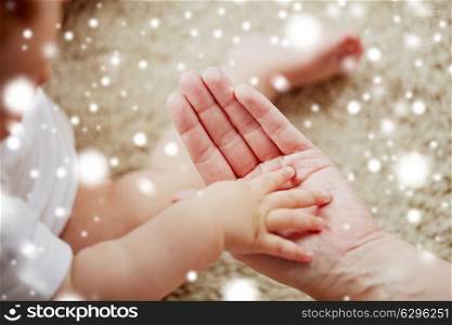 family, charity and people concept - close up of little baby and mother hands over snow. close up of little baby and mother hands