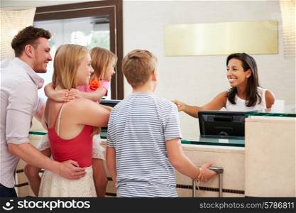 Family Checking In At Hotel Reception