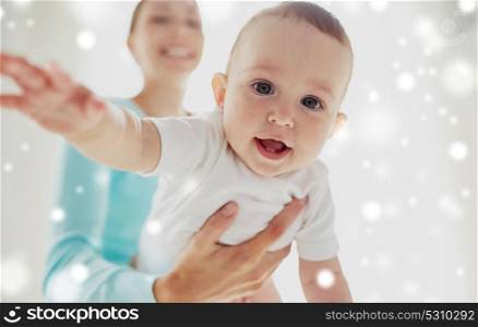 family, child and babyhood concept - close up of happy smiling young mother with little baby over snow. happy young mother with little baby
