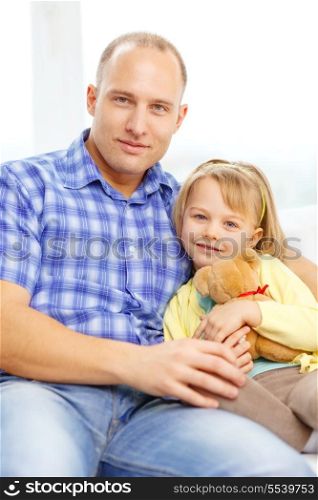 family, child and happiness concept - smiling father and daughter with teddy bear at home