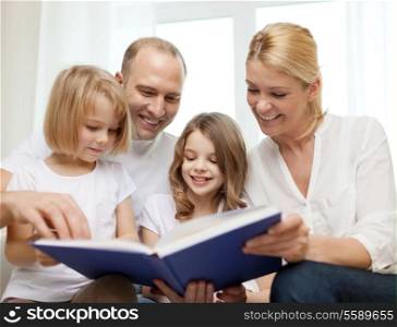 family, child and home concept - smiling family and two little girls with book at home