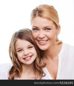 family, child and home concept - smiling mother and little girl at home