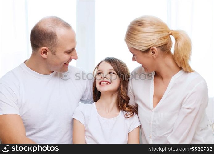 family, child and home concept - smiling parents and little girl at home