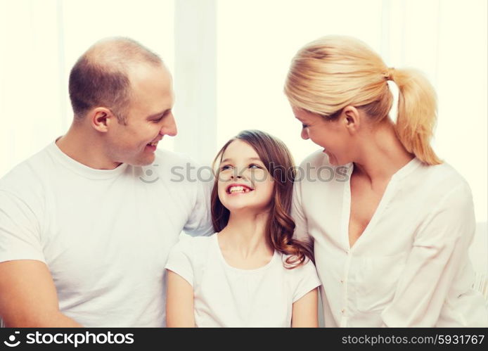 family, child and home concept - smiling parents and little girl at home