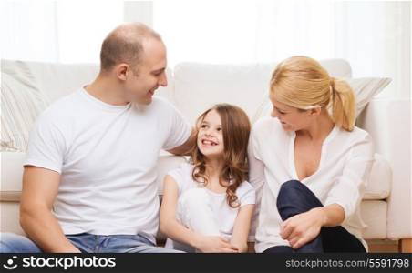 family, child and home concept - smiling parents and little girl sitting on floor at home