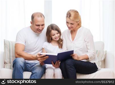 family, child and home concept - smiling parents and little girl with book at home