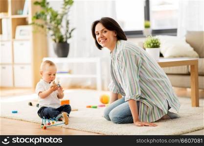 family, child and motherhood concept - happy mother with little baby son playing developmental toys at home. happy mother with little baby son playing at home