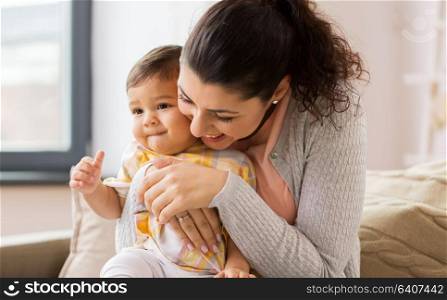 family, child and motherhood concept - happy smiling mother with little baby daughter at home. happy smiling mother with baby daughter at home