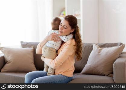 family, child and motherhood concept - happy smiling young mother hugging little baby at home. happy young mother hugging little baby at home