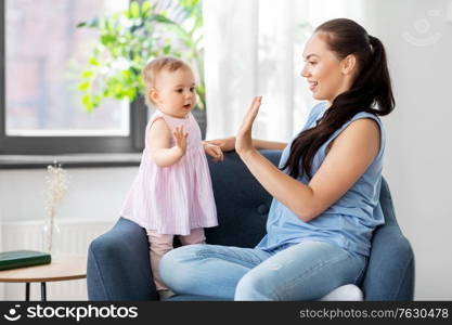 family, child and motherhood concept - portrait of happy smiling mother with little baby daughter playing clapping game at home. happy mother playing with baby daughter at home