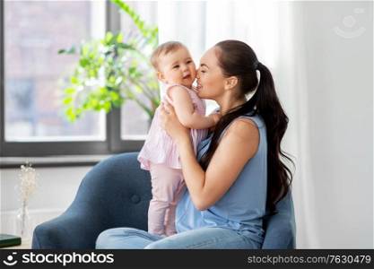 family, child and motherhood concept - portrait of happy smiling mother with little baby daughter sitting in chair at home. happy mother with little baby daughter at home