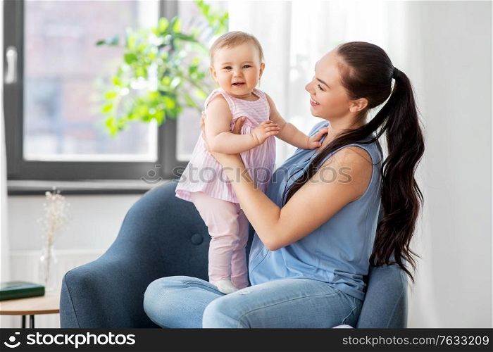 family, child and motherhood concept - portrait of happy smiling mother with little baby daughter sitting in chair at home. happy mother with little baby daughter at home