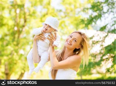 family, child and parenthood concept - happy mother holding and raising little baby up in park