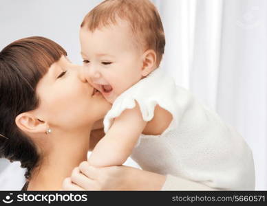 family, child and parenthood concept - happy mother kissing smiling baby