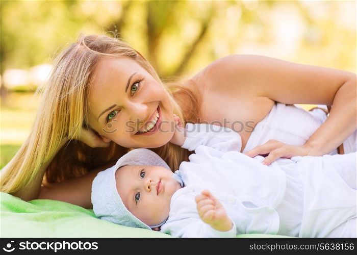 family, child and parenthood concept - happy mother lying with little baby on blanket in park