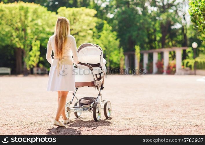 family, child and parenthood concept - happy mother walking with baby stroller in park from back