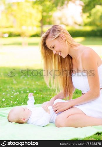 family, child and parenthood concept - happy mother with little baby lying on blanket in park