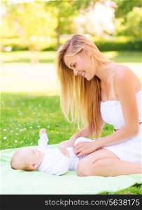 family, child and parenthood concept - happy mother with little baby lying on blanket in park