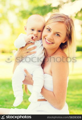 family, child and parenthood concept - happy mother with little baby sitting on blanket in park