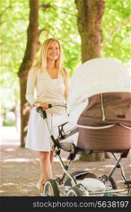 family, child and parenthood concept - happy mother with stroller in park