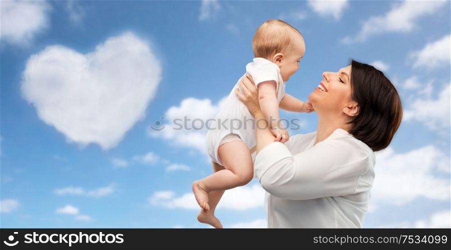 family, child and parenthood concept - happy smiling middle-aged mother holding little baby daughter over blue sky and heart shaped cloud background. happy middle-aged mother with little baby daughter