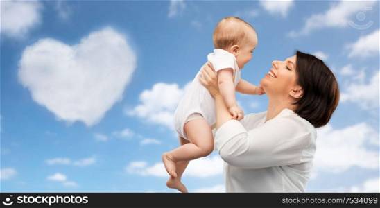 family, child and parenthood concept - happy smiling middle-aged mother holding little baby daughter over blue sky and heart shaped cloud background. happy middle-aged mother with little baby daughter