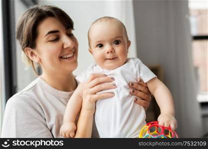 family, child and parenthood concept - happy smiling young mother holding little baby daughter over grey background. happy young mother holding little baby daughter