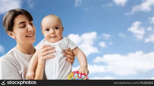 family, child and parenthood concept - happy smiling young mother holding little baby daughter over blue sky and clouds background. happy young mother holding little baby daughter