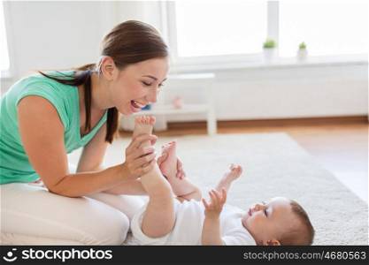 family, child and parenthood concept - happy smiling young mother playing with little baby or doing gymnastics exercise for toddlers at home