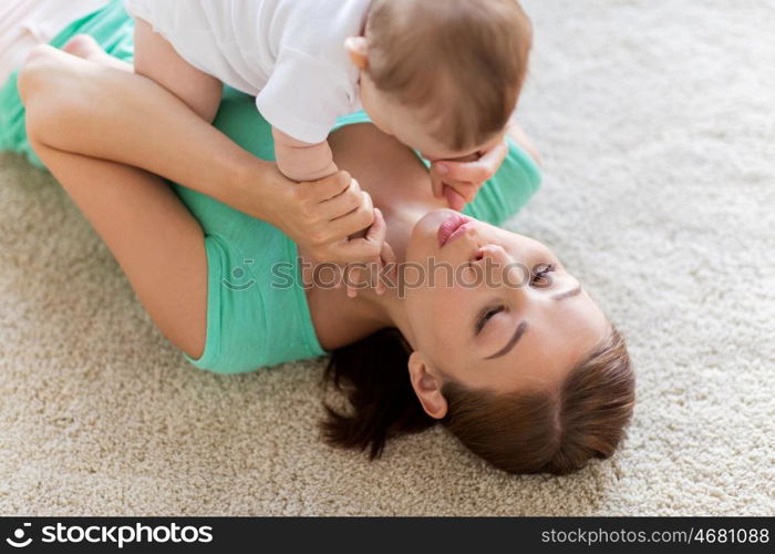 family, child and parenthood concept - happy smiling young mother playing with little baby at home