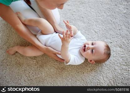 family, child and parenthood concept - happy smiling young mother playing with little baby at home. happy mother playing with baby at home