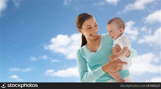 family, child and parenthood concept - happy smiling young mother with little baby over blue sky and clouds background