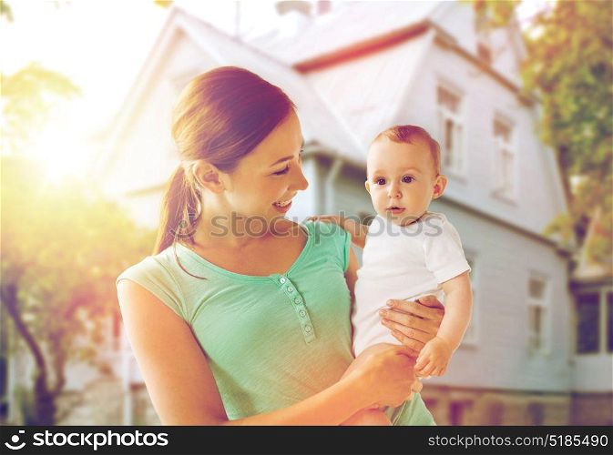 family, child and parenthood concept - happy smiling young mother with little baby over holidays lights background. happy young mother with baby over holidays lights