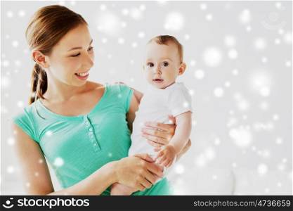 family, child and parenthood concept - happy smiling young mother with little baby over snow. happy young mother with little baby