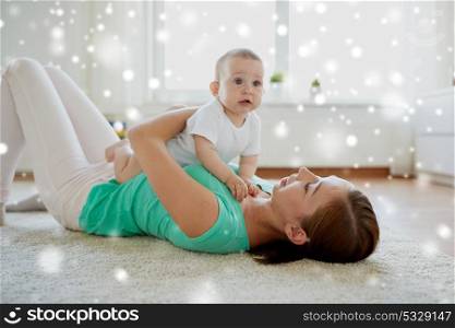 family, child and parenthood concept - happy young mother playing with little baby at home over snow. happy mother playing with baby at home