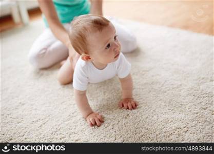 family, child and parenthood concept - mother with little baby on floor at home