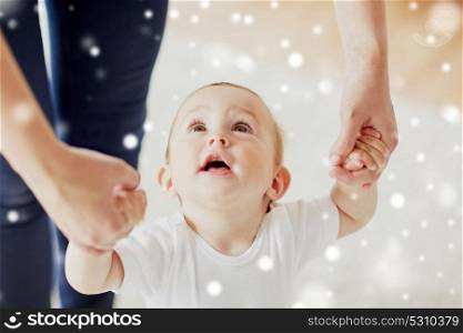 family, child, childhood and parenthood concept - happy little baby learning to walk with mother help over snow. happy baby learning to walk with mother help
